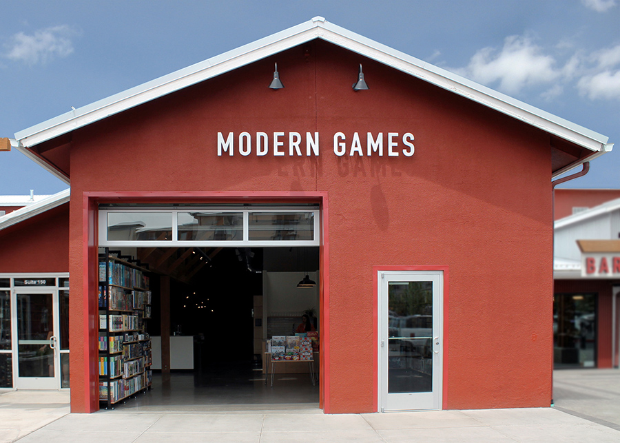The minimalist red storefront featuring roll-up glass garage doors and clean white lettering